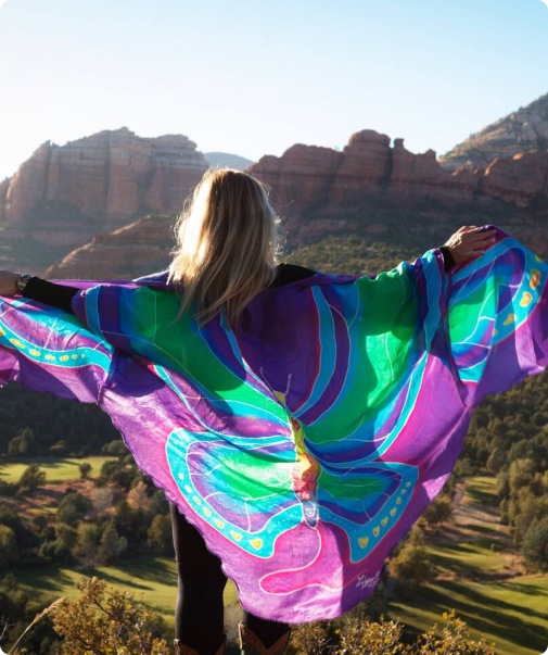 A woman standing on top of a hill with her arms spread out.