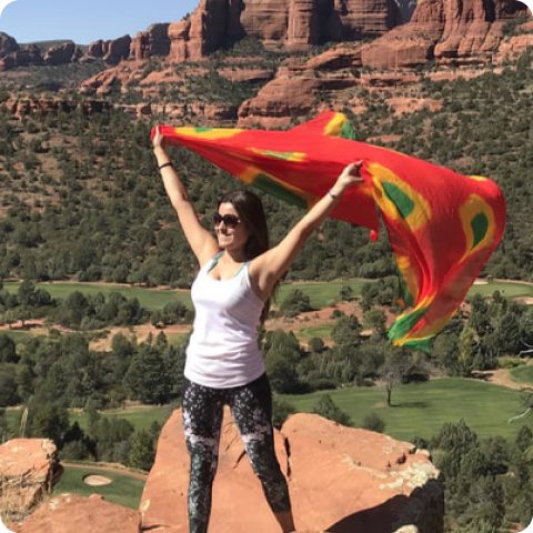 A woman standing on top of a mountain holding a flag.