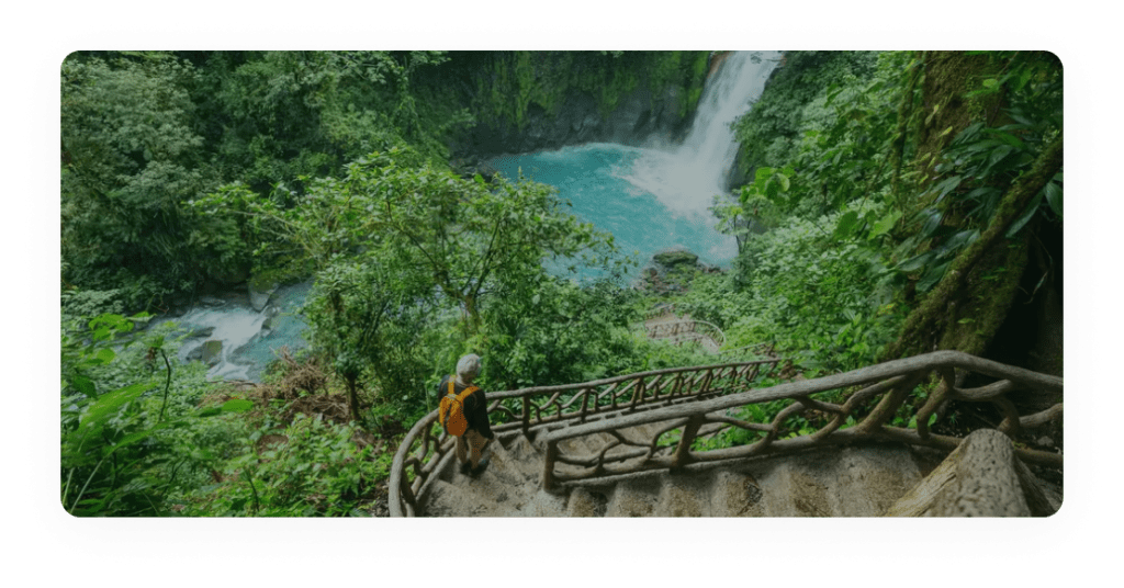 A person walking up stairs near a waterfall.