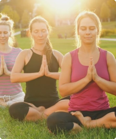 Three women are sitting in the grass with their hands folded.