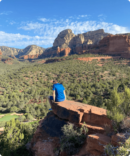 A man sitting on top of a rock.