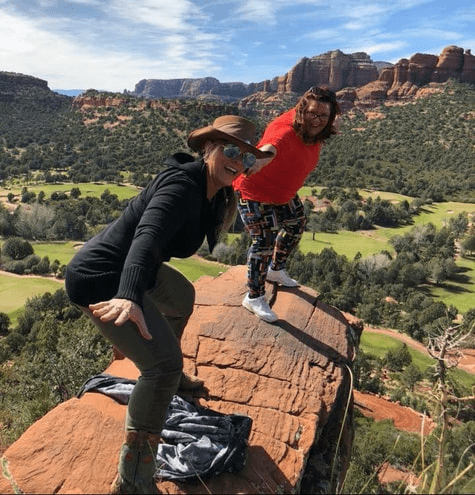 Two people standing on a rock ledge in the desert.