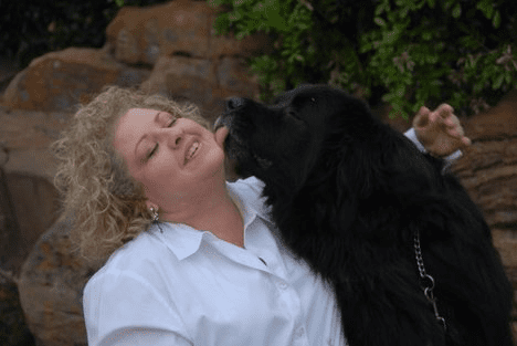 A woman and her dog are kissing each other.
