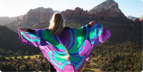 A woman in a butterfly dress standing on top of a hill.