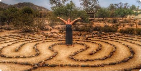 A woman standing in the middle of an outdoor labyrinth.