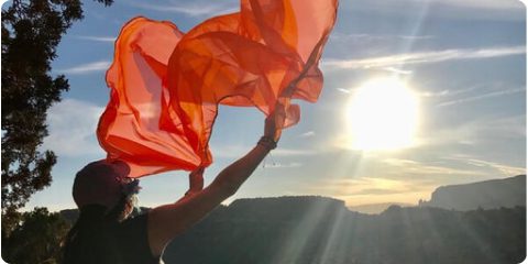 A person holding onto a red cloth in the air