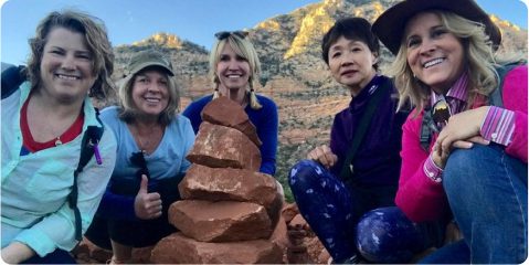 Three women are posing for a picture with rocks.