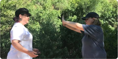 Two people standing in front of a tree.