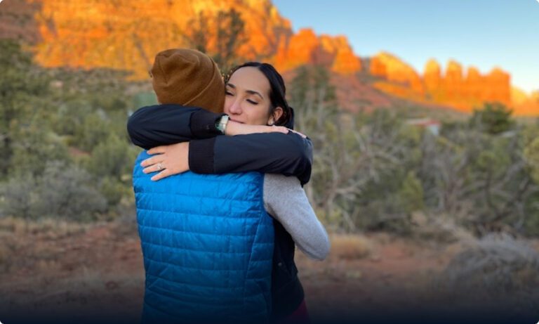 Two people hugging each other in the desert.