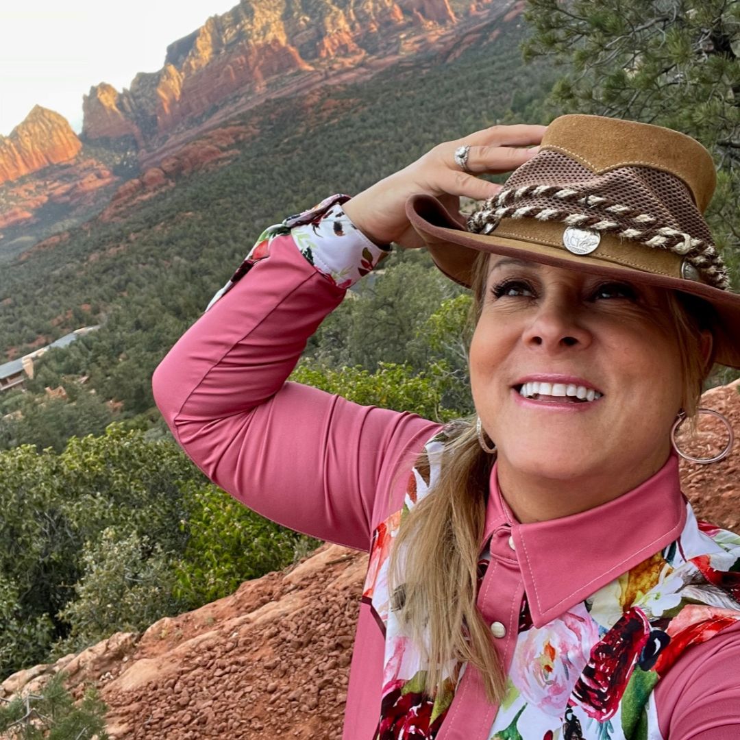 A woman in pink shirt and hat near trees.